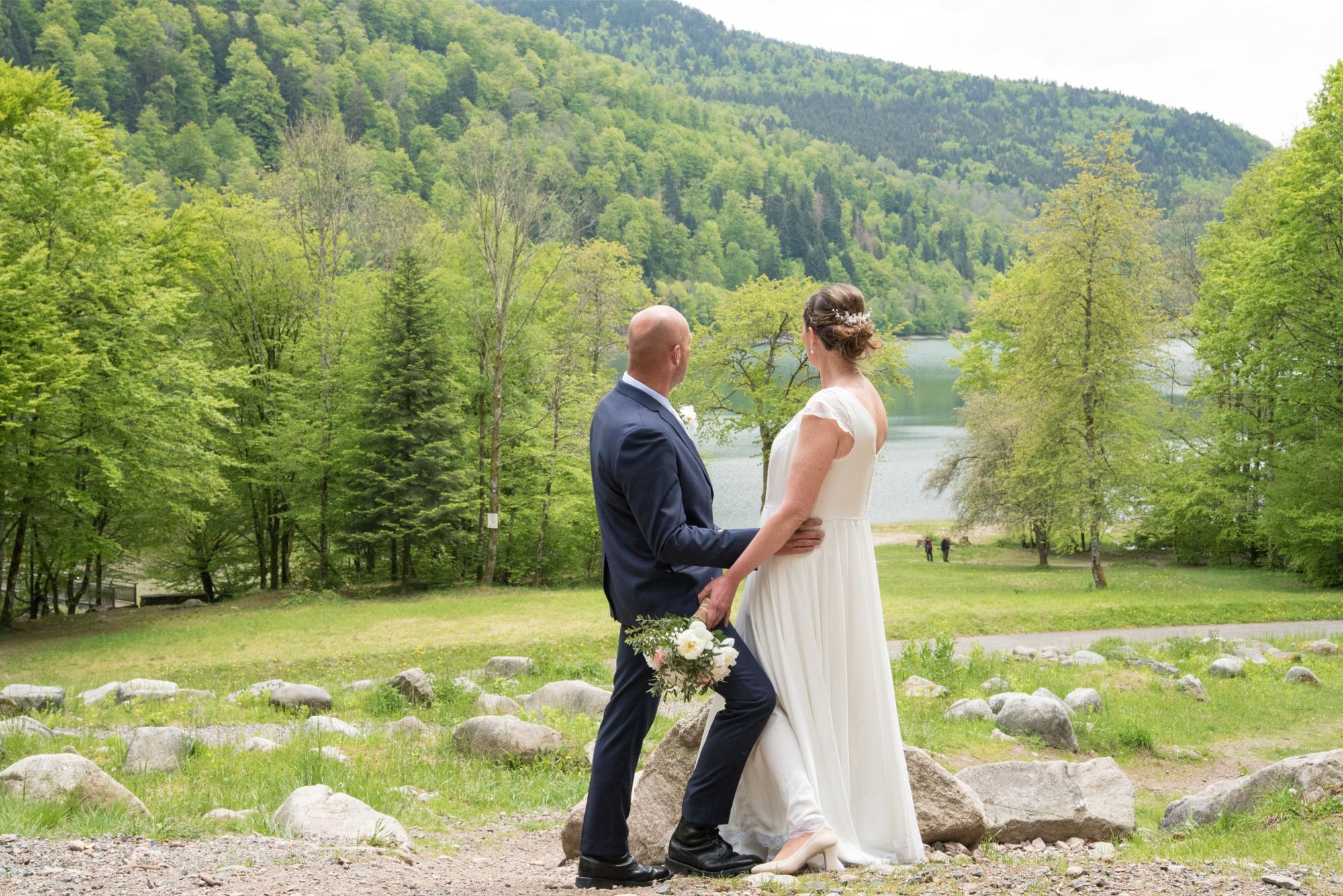 photo de mariés de dos devant le lac, profitent de la vue, mariage bohème chic dans le grand est