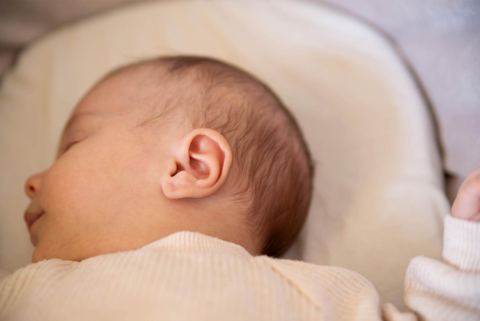 photo de détail d'une oreille d'un bébé lors d'une séance naissance à domicile à Besançon