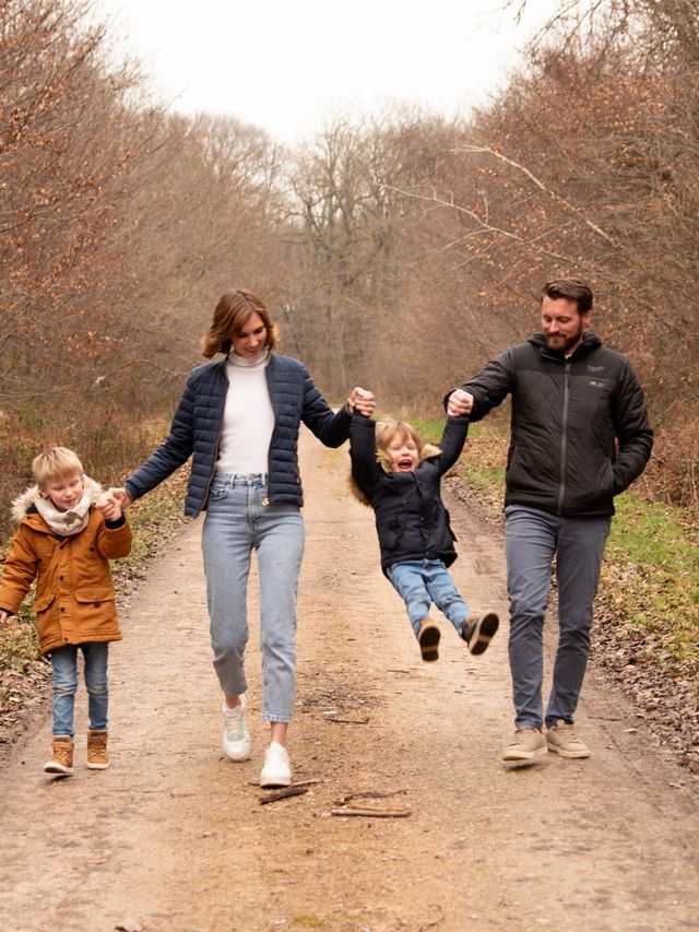 Photo de famille qui joue et rigole dans la forêt