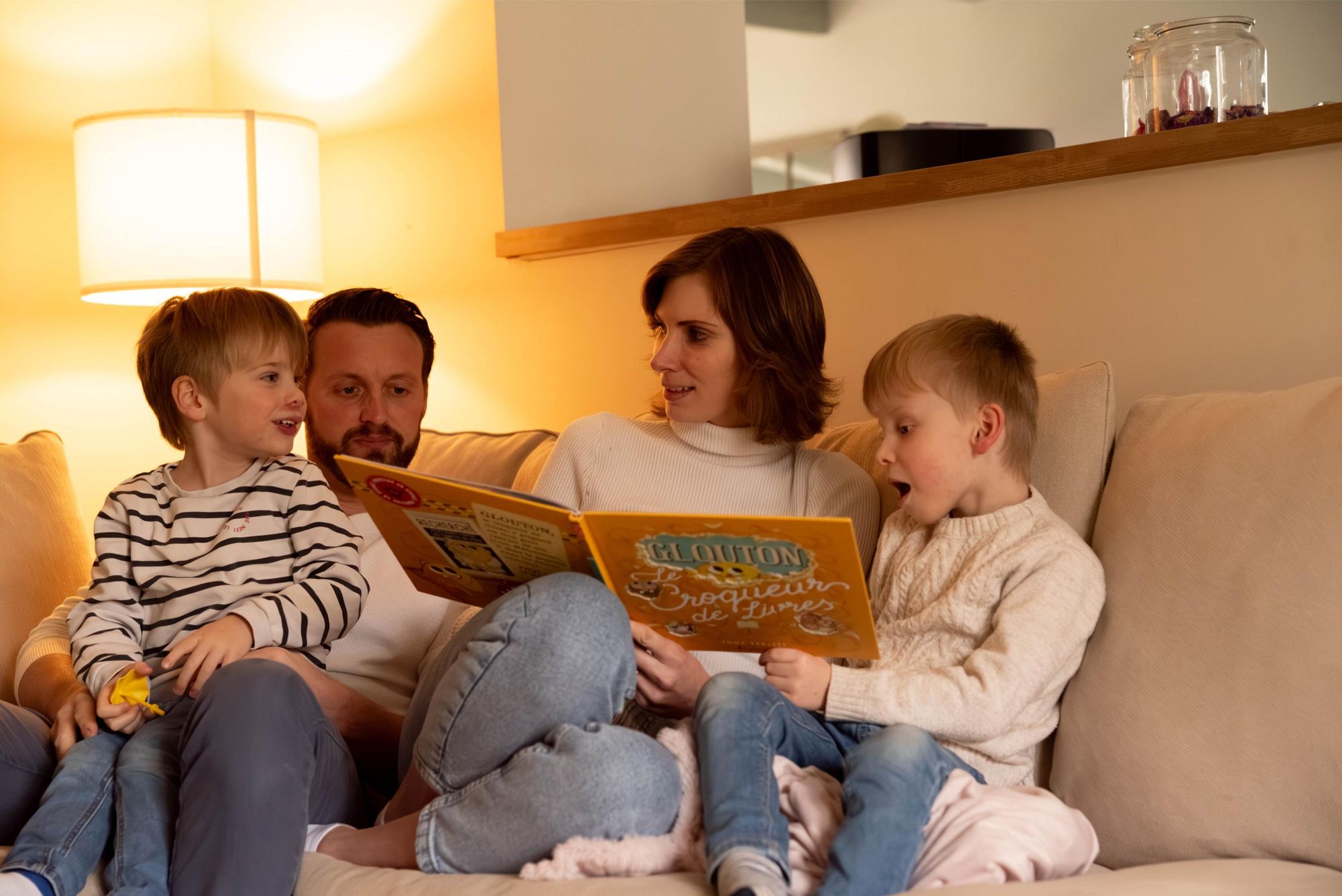 photo de famille lors d'une séance lifestyle  à Besançon. les enfants écoutent leurs parents qui racontent des histoires,