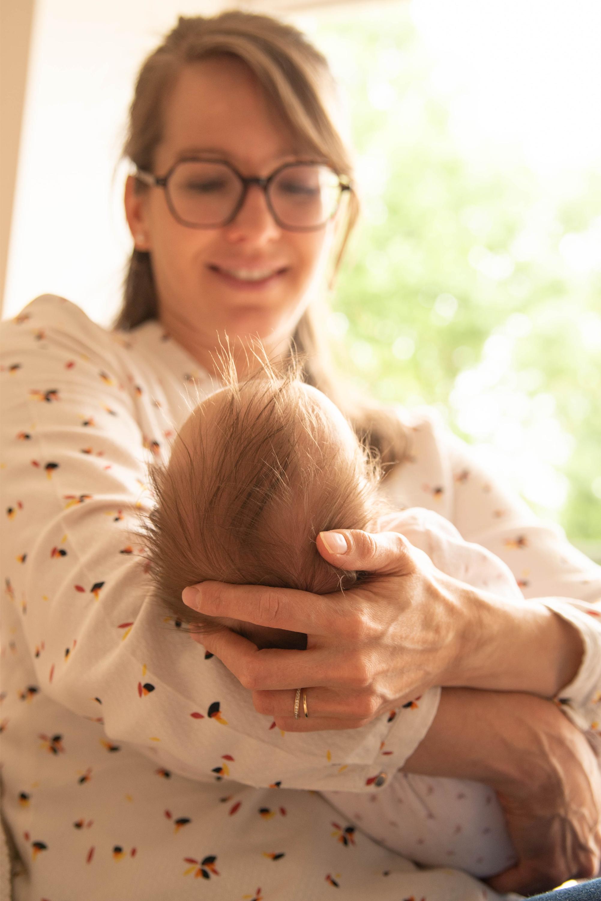 photo d'une maman qui tient son bébé dans les bras regard attendri lors d'une session naissance à Besançon
