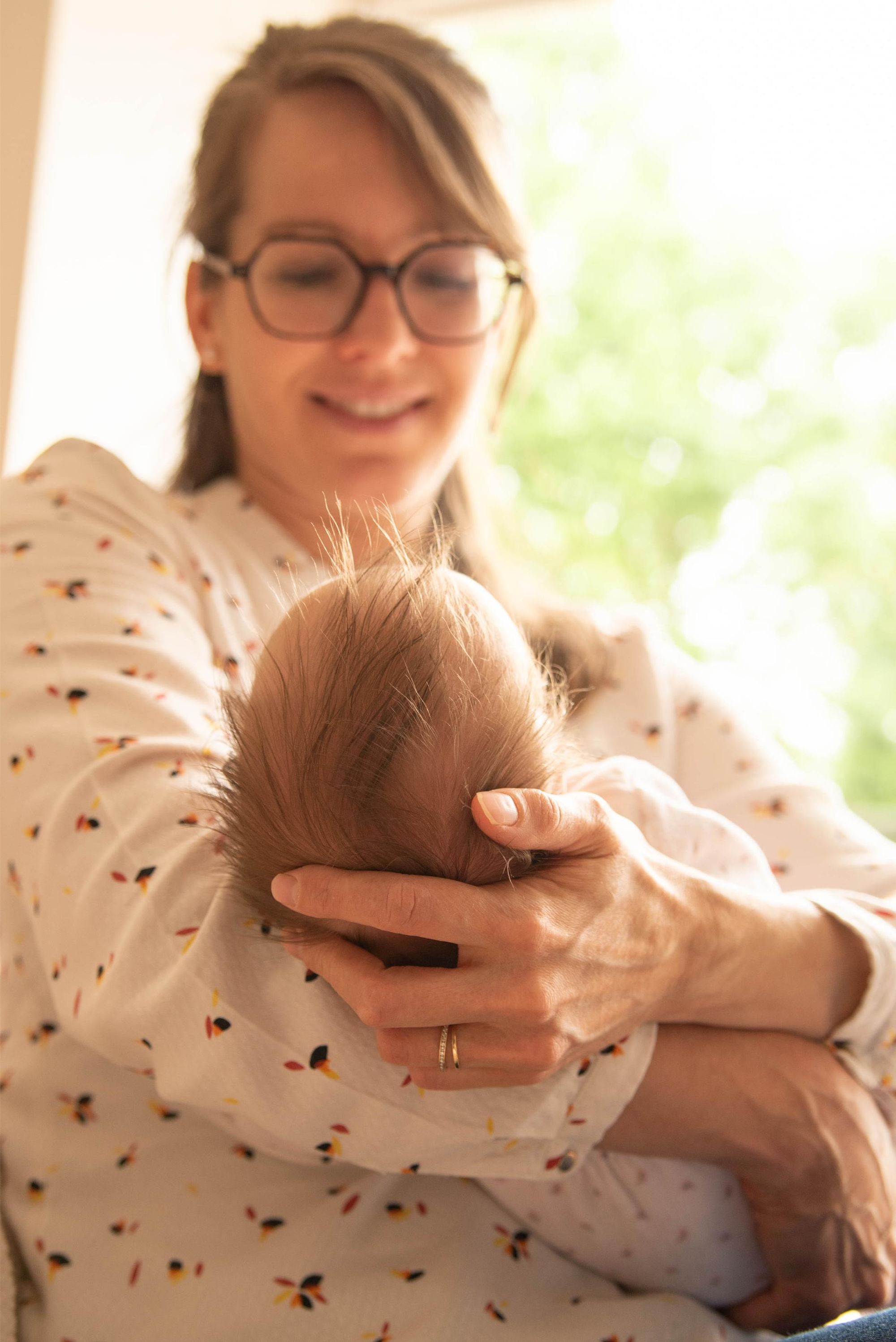 photo d'une maman qui tient son bébé dans les bras regard attendri lors d'une session naissance à Besançon