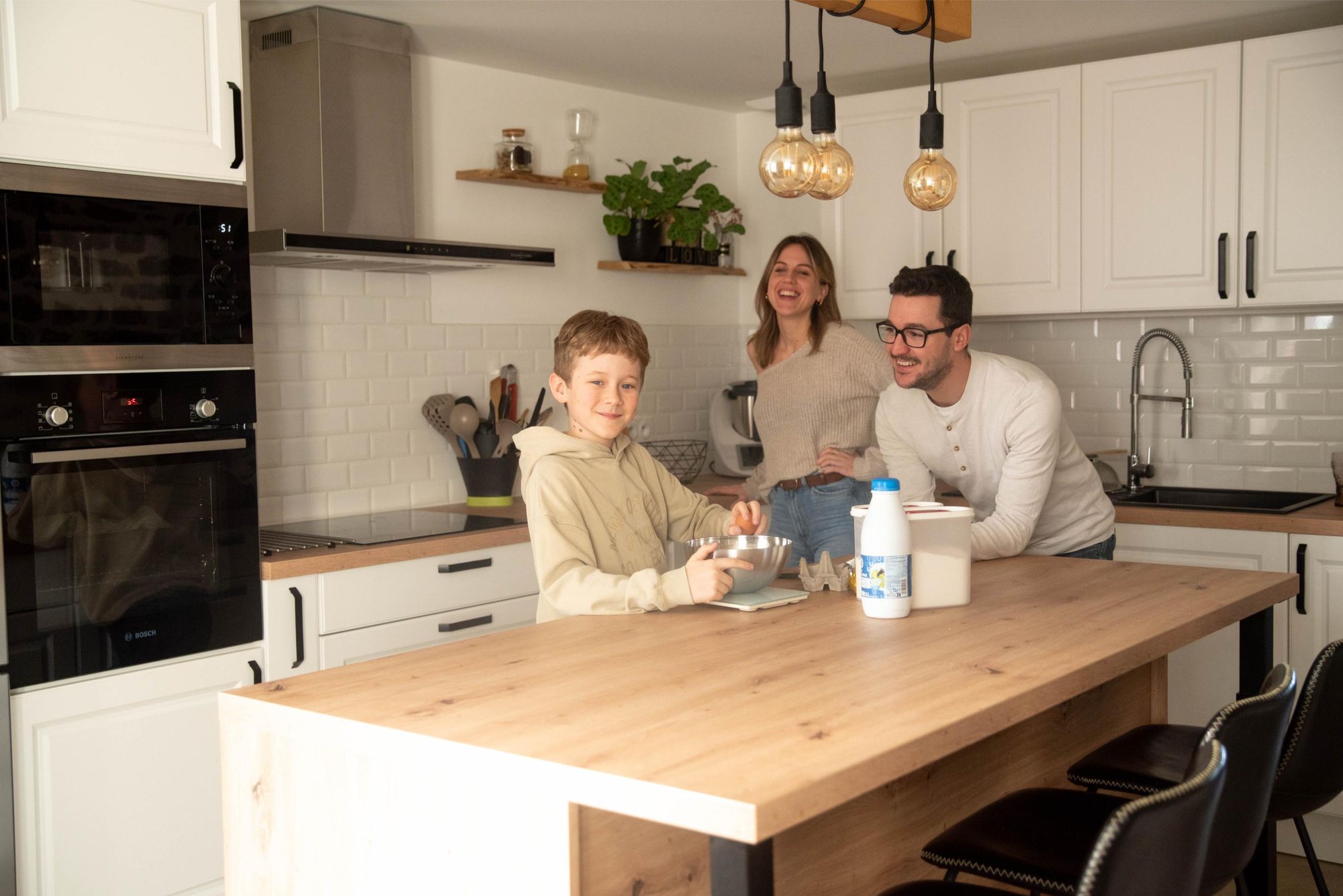 enfant qui prépare des crepes sous le regard attendri de ses parents lors d'une séance lifestyle à Besançon