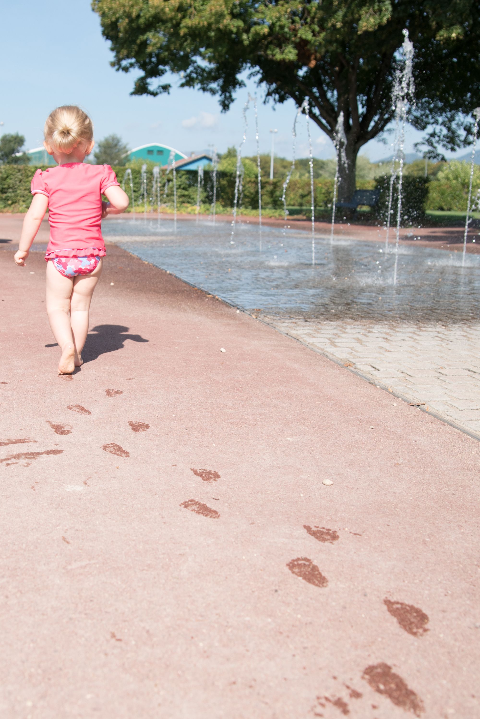 enfant qui court à coté d'un jeu d'eau de dos lors d'une session famille dans le grand est