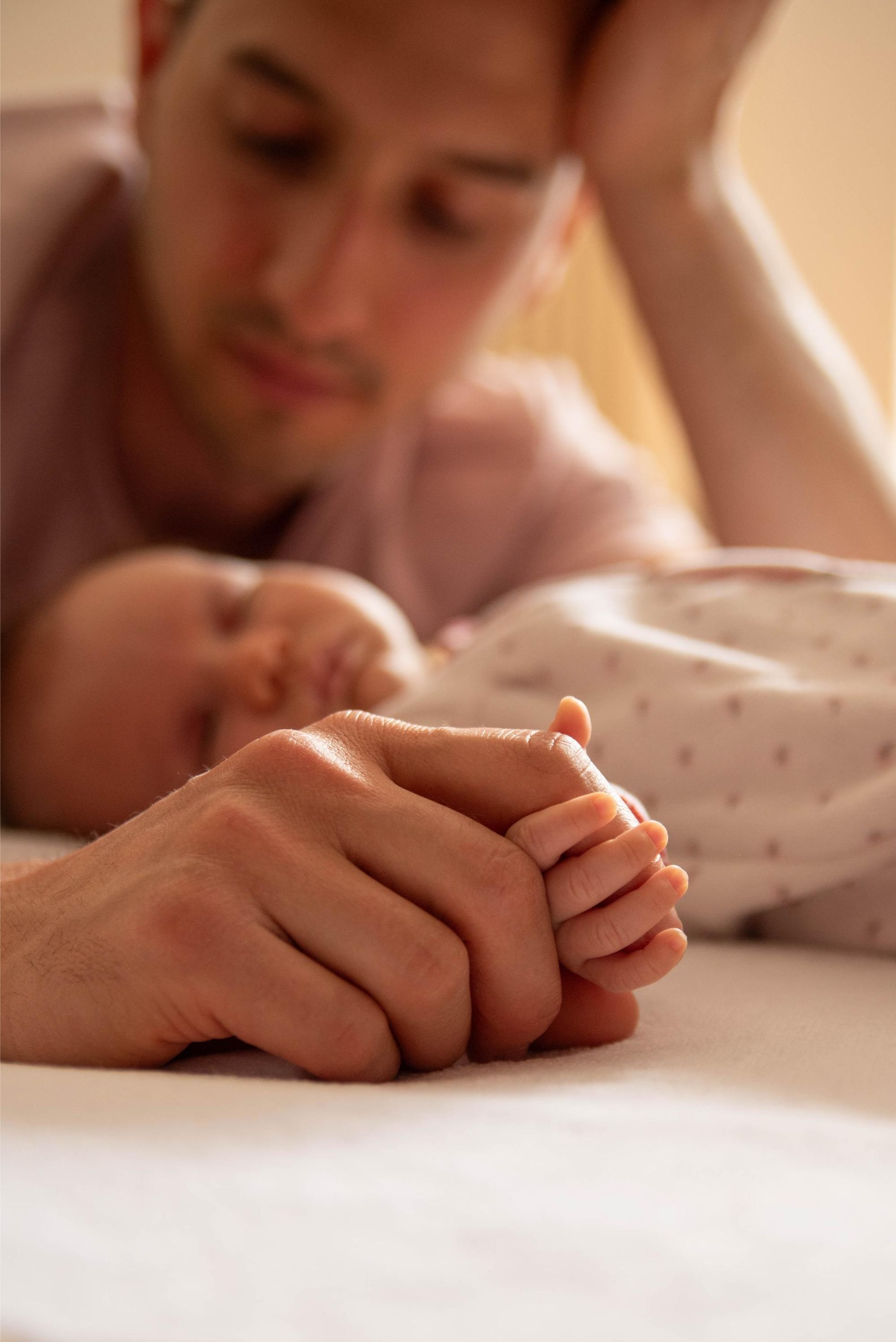 petite main de bébé qui tient le doigt de son père lors d'une session photo de naissance à domicile proche Besançon