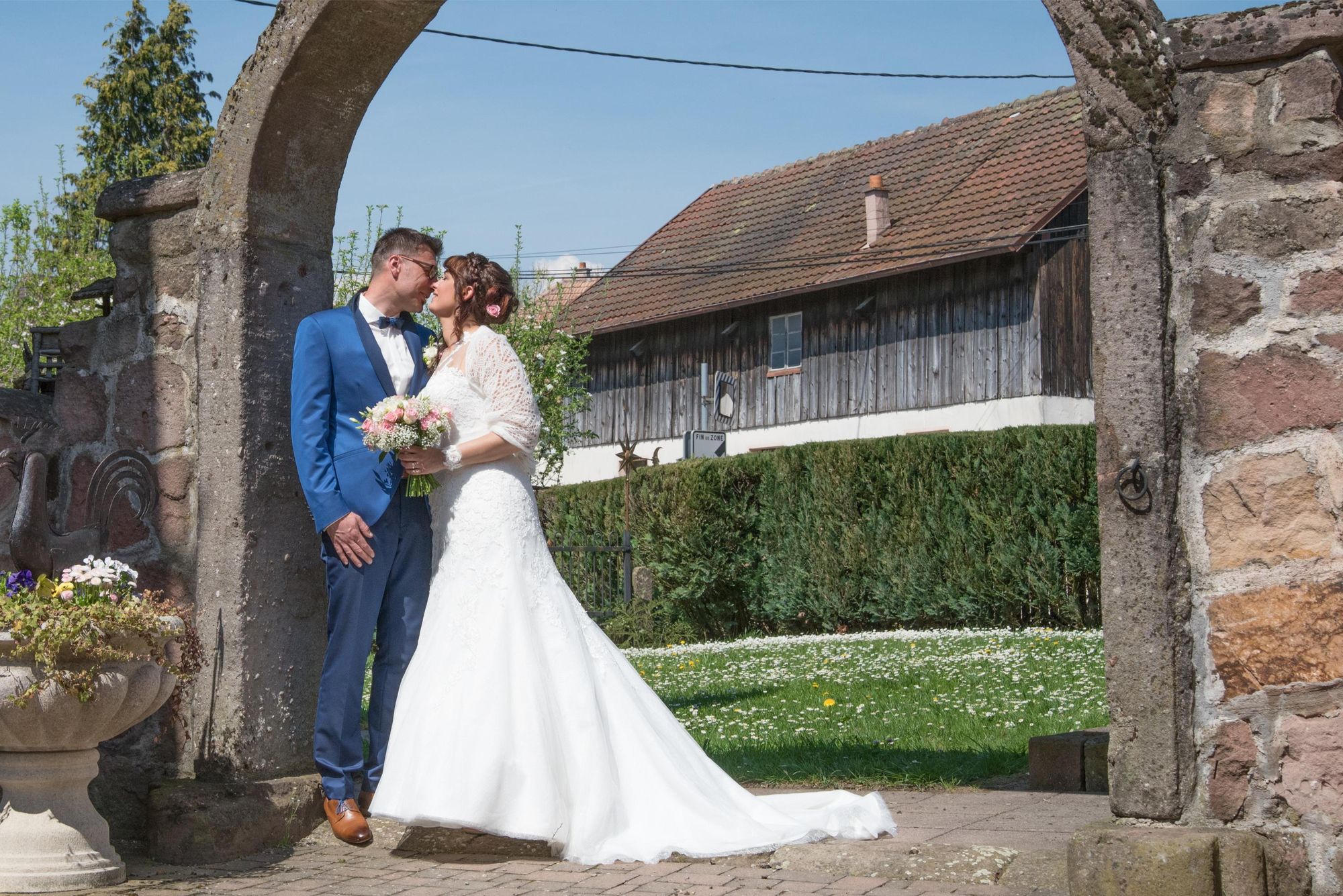 marié s'embrassant sous un arche en pierre, très amoureux, mariage naturel et élégant dans le grand est