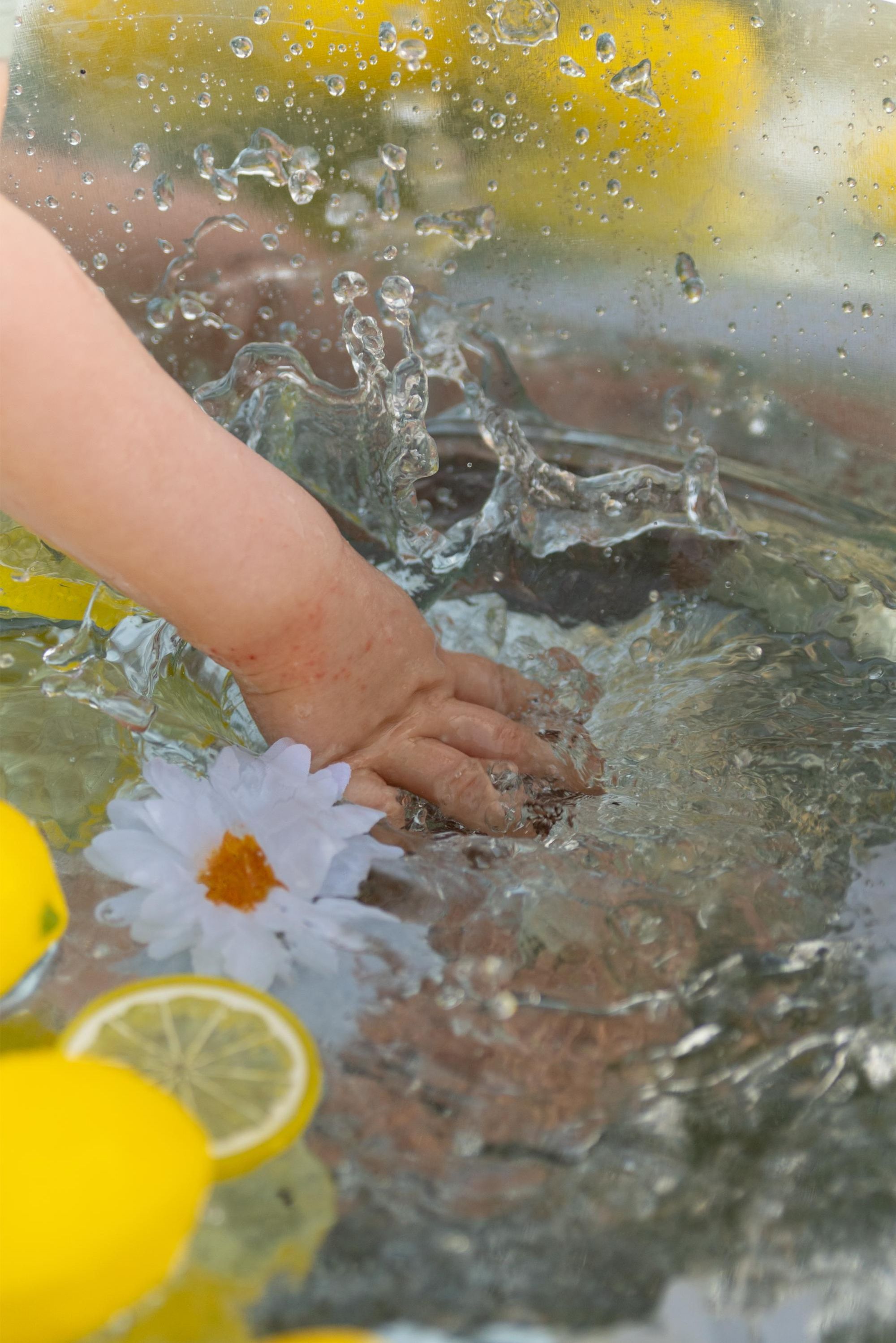 détail d'une main dans l'eau lors d'une mini session photo enfant avec des citrons à coté de Besançon en extérieur 