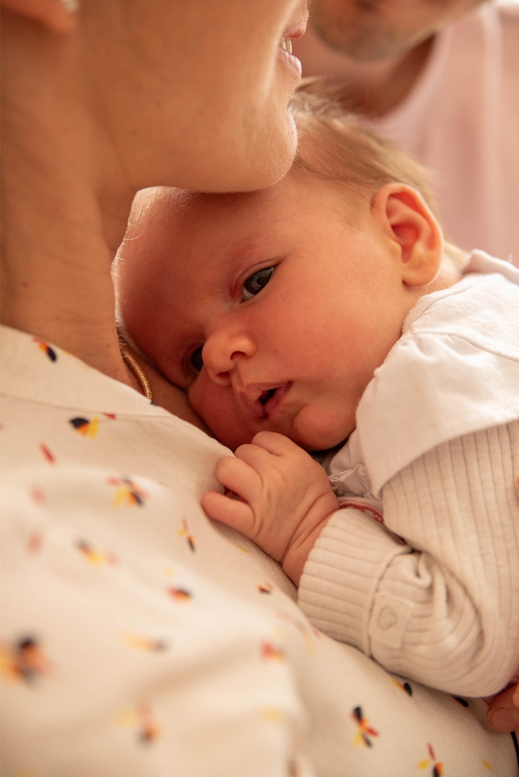photo d'une petite fille lovée dans le cou de sa maman lors d'une session naissance à domicile à Besançon