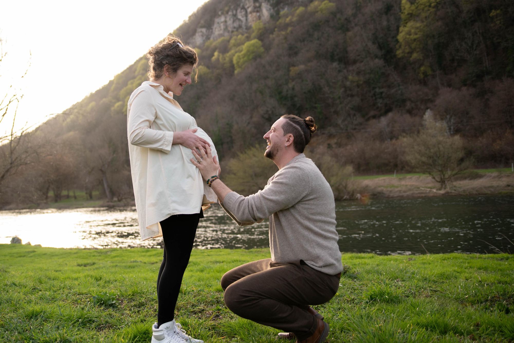 photo d'un couple heureux de l'arrivée de leur futur bébé, prise lors d'une session photo grossesse en extérieur proche de Besançon