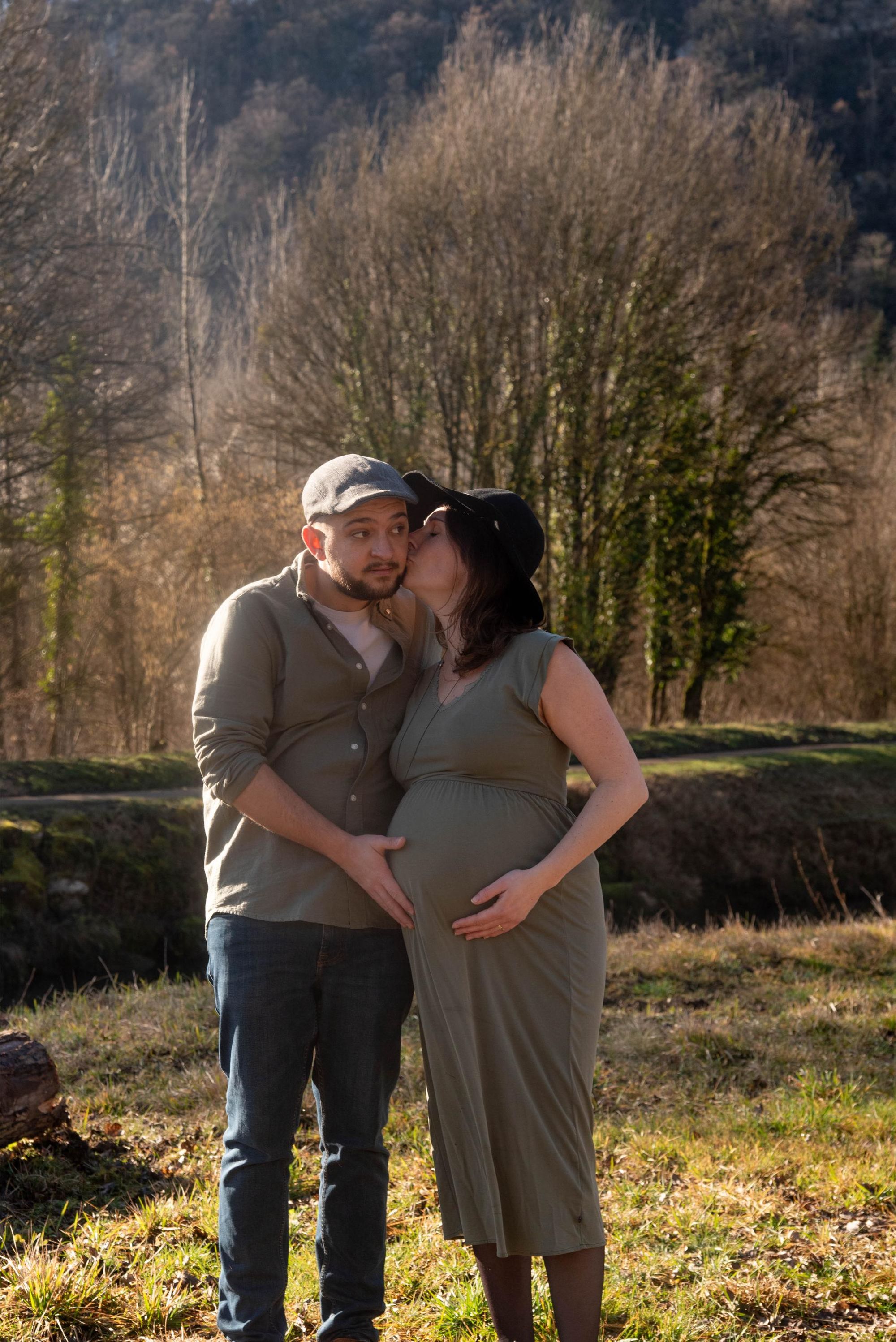 photo d'une future maman qui embrasse son compagnon lors d'une séance photo grossesse en extérieur, près de Besançon