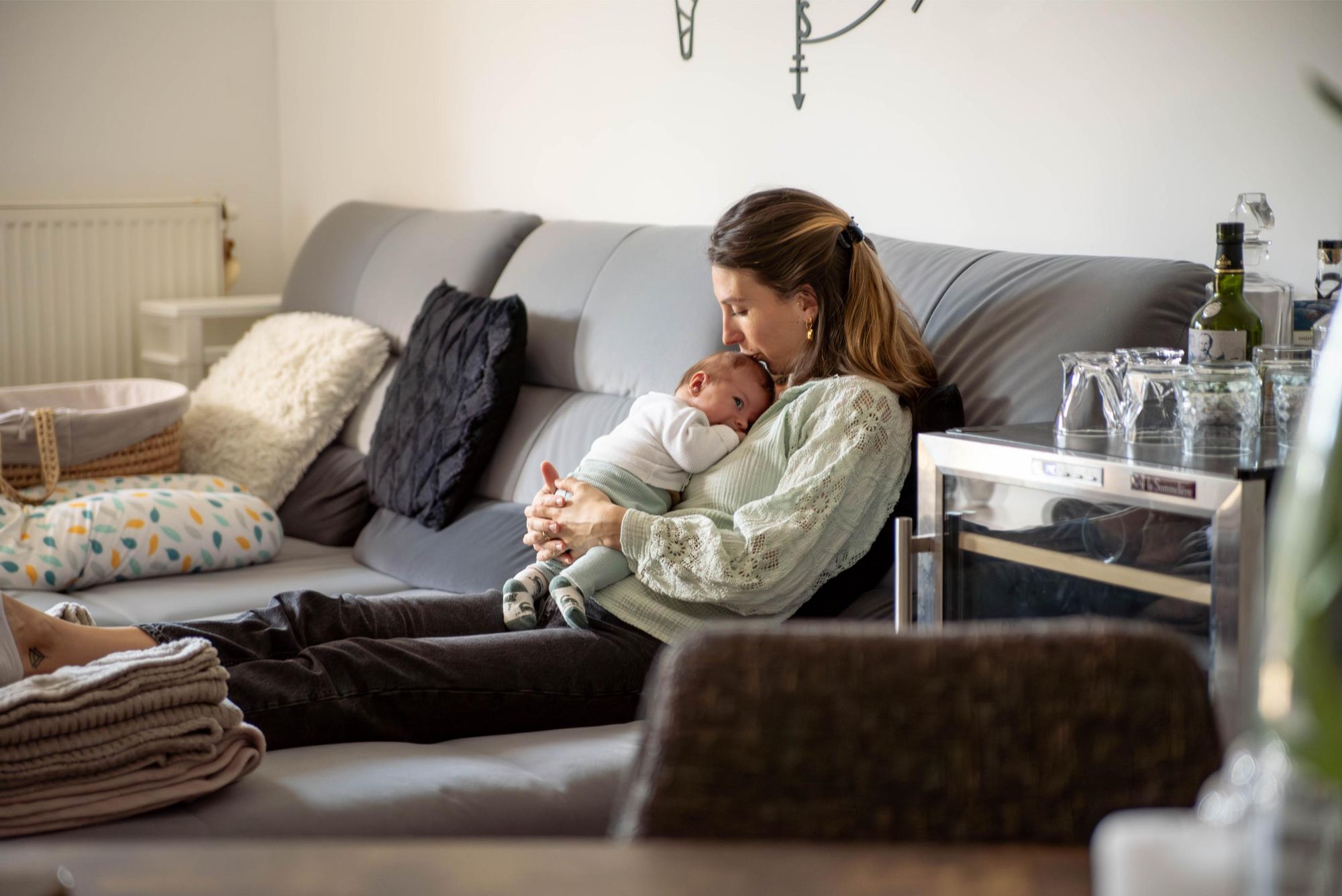 une maman et son nouveau né assis dans leur canapé lors d'une séance photo naissance lifestyle à Besançon