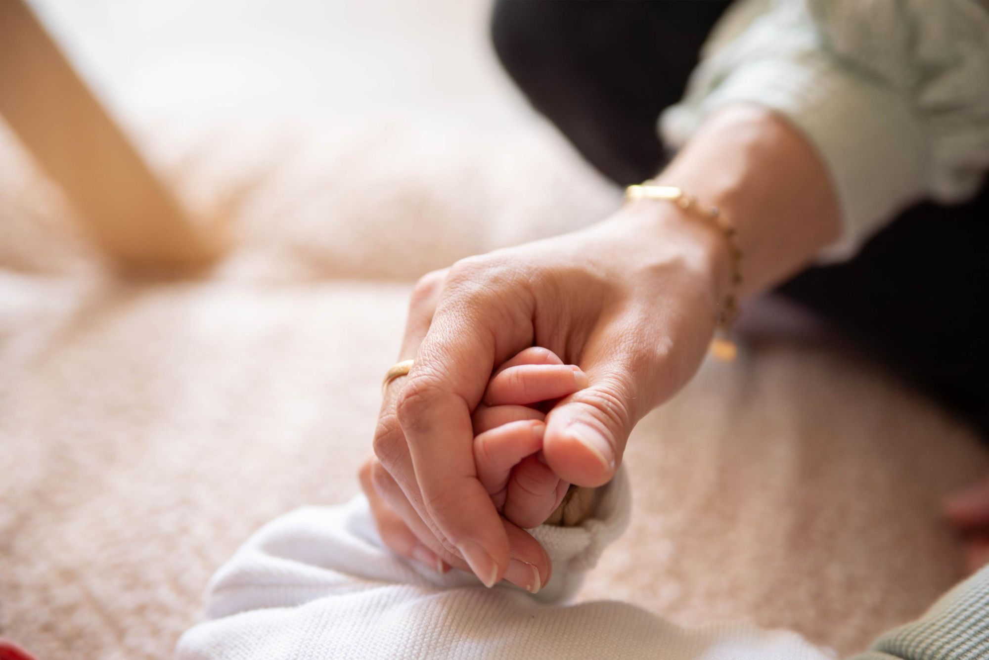photo d'une main de bébé tenue dans celle de sa maman lors d'une séance photo naissance à Besançon