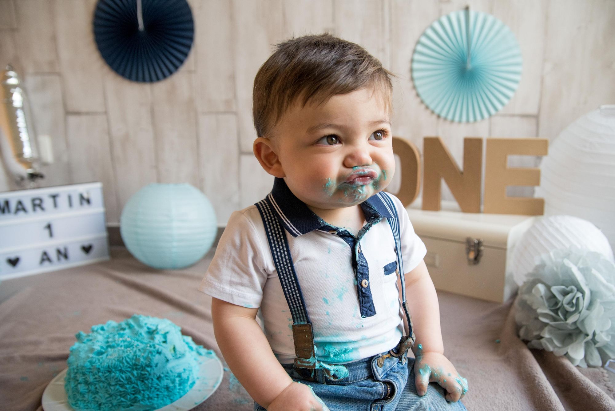 photo d'un enfant qui fait une grimace adorable lors d'un smash the cake à domicile, pour un anniversaire dans le grand est 