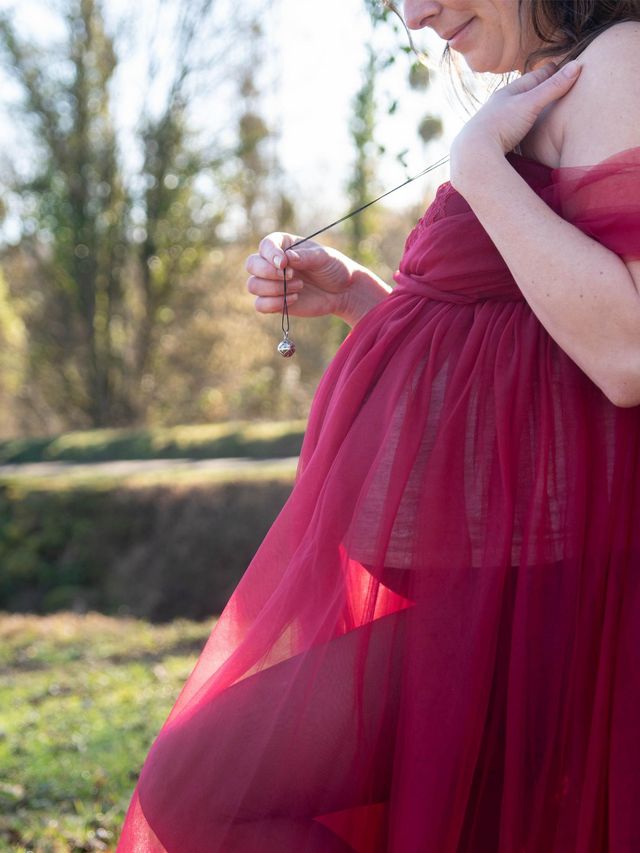 Photo de grossesse, ventre rond, robe rouge en extérieur