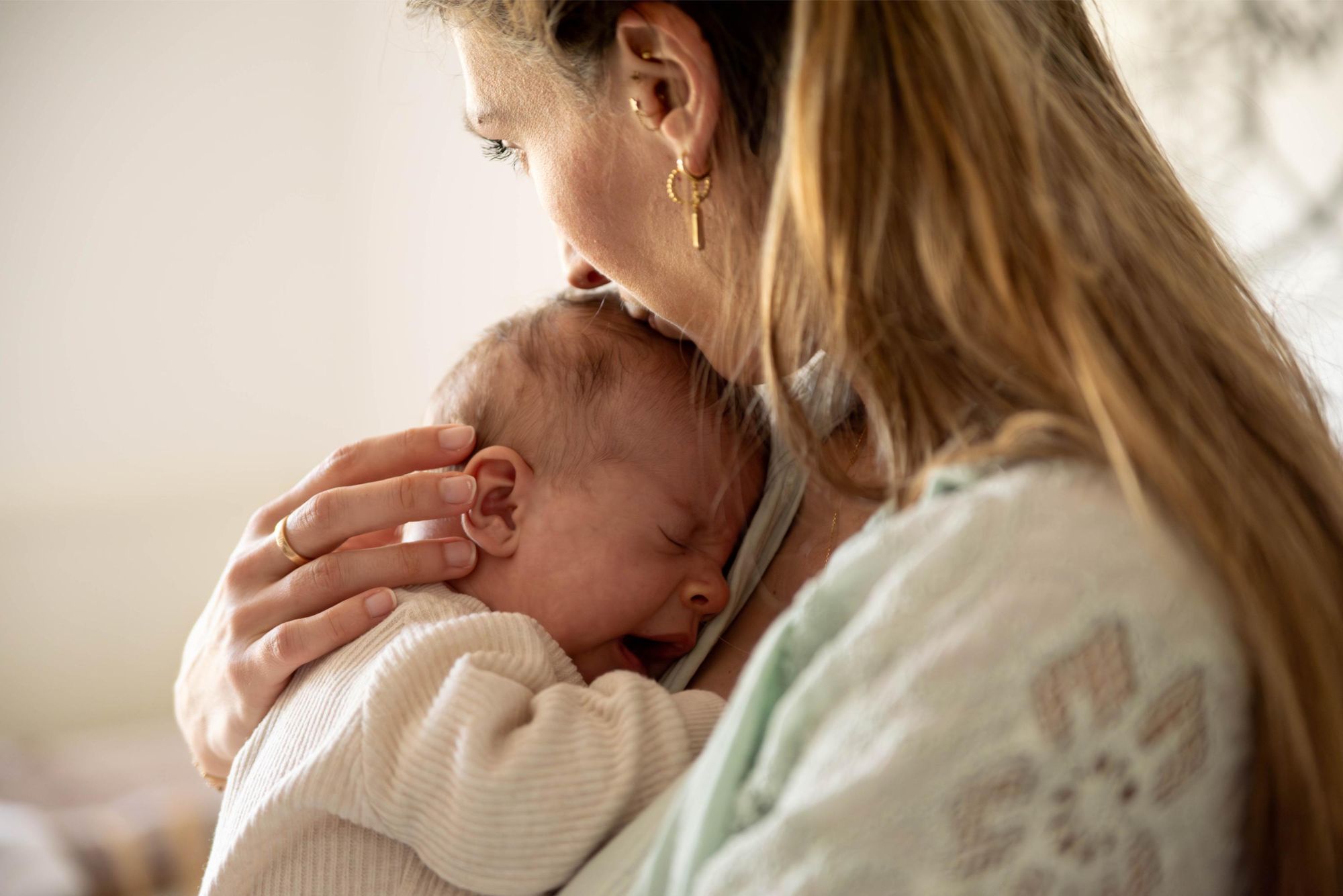 photo d'un bébé qui baille dans les bras de sa maman lors d'une séance photo lifestyle à domicile à Besançon